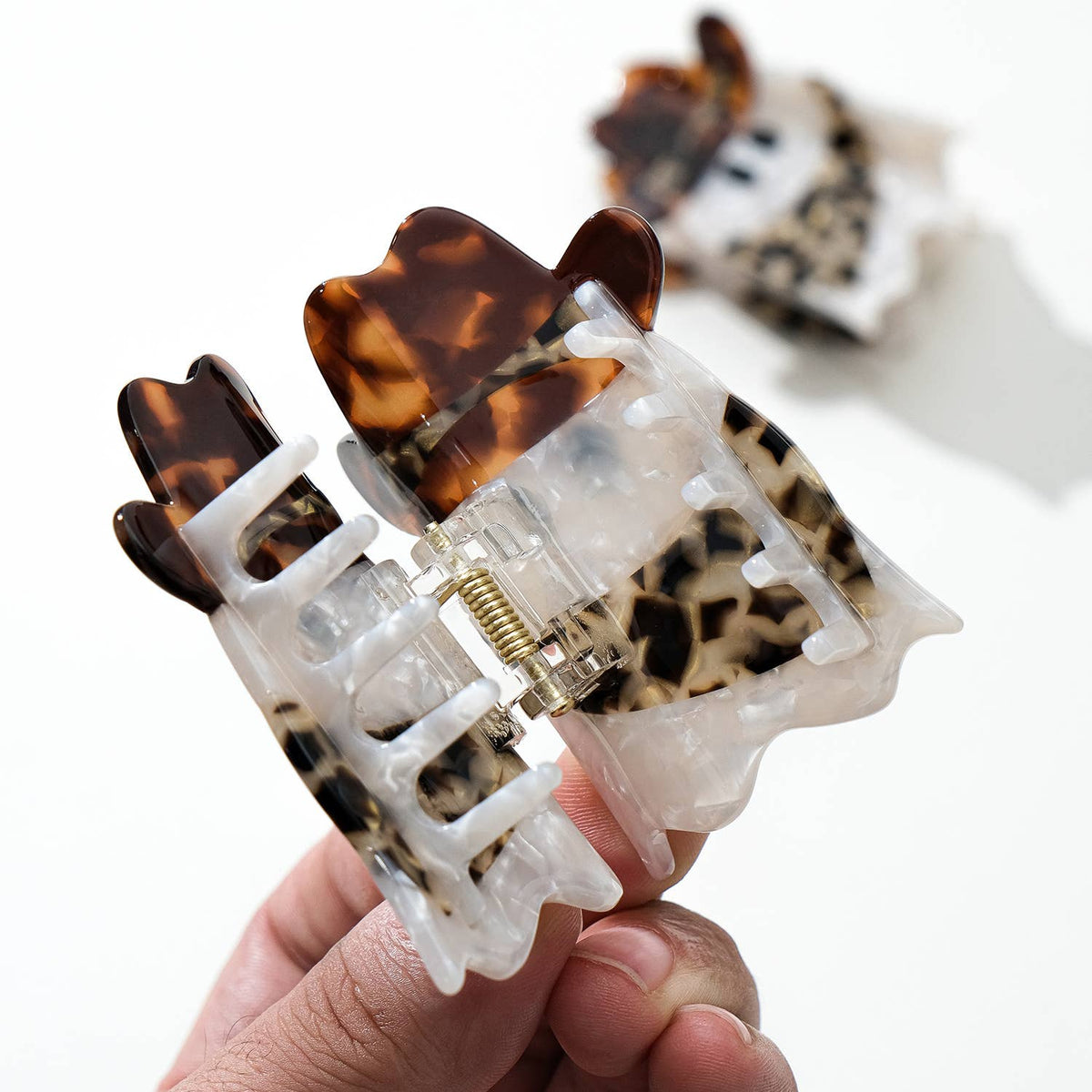 Two ghost-shaped hair clips with tortoiseshell cowbory scarf and hat accents on a white background