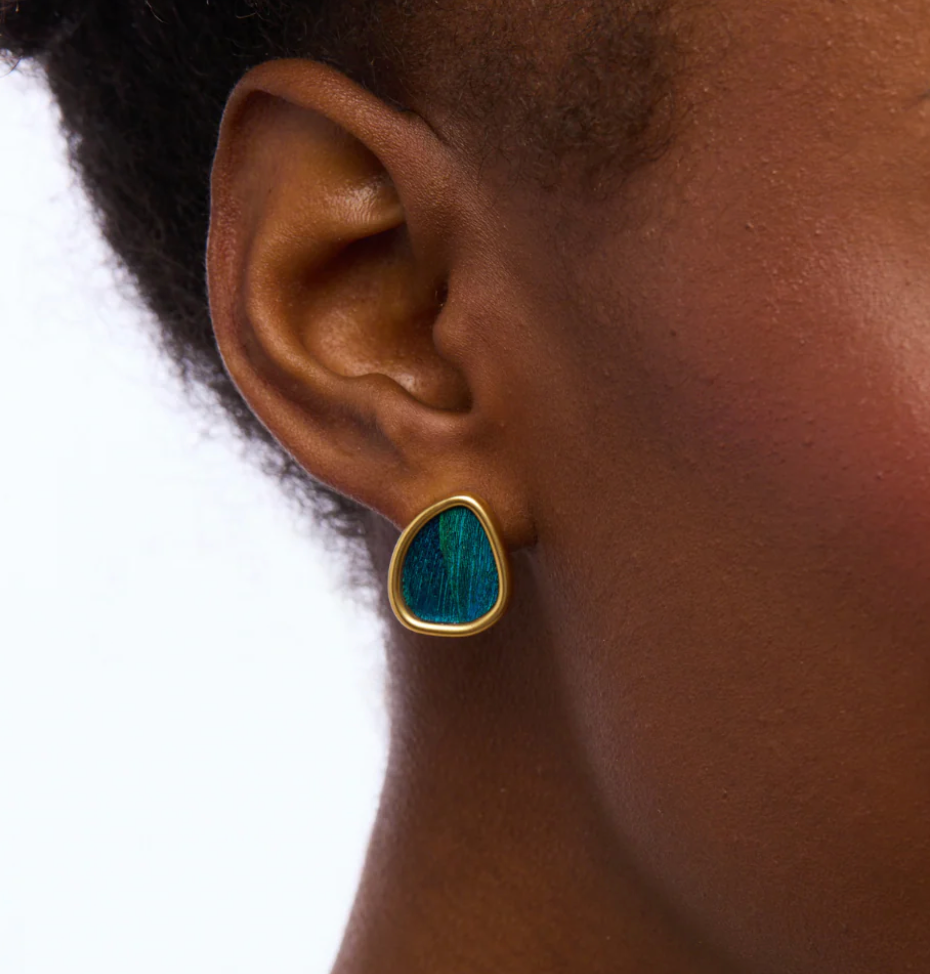 24 karat gold plated blue feather stud earring on a model's ear with a white background