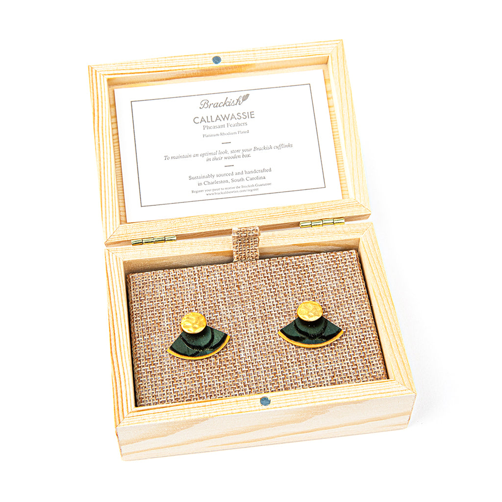 Wooden jewelry box with green and gold earrings on a white background