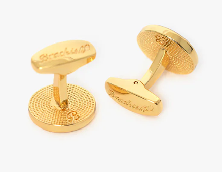 Round gold cufflinks with engraved Brackish logos on a white background