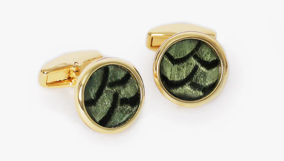 Round gold cufflinks with green and black feather inlay on a white background