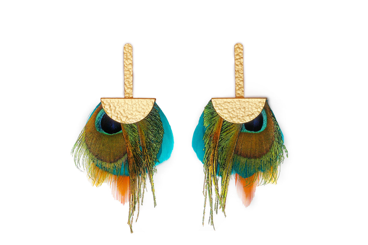 Pair of gold earrings with dangling peacock feathers on a white background