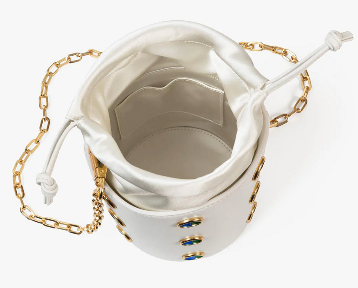 Overhead view of interior of white leather bucket bag with gold chain shoulder strap on a white background