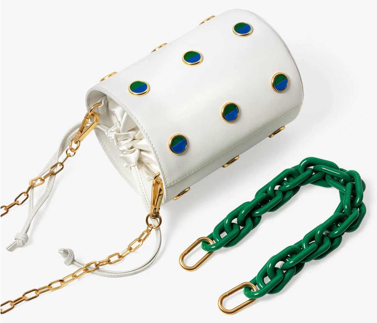 White leather bucket bag with thin gold link shoulder strap and alternate chunky green chain hand strap. Bag features green and blue feather polka dot inlays