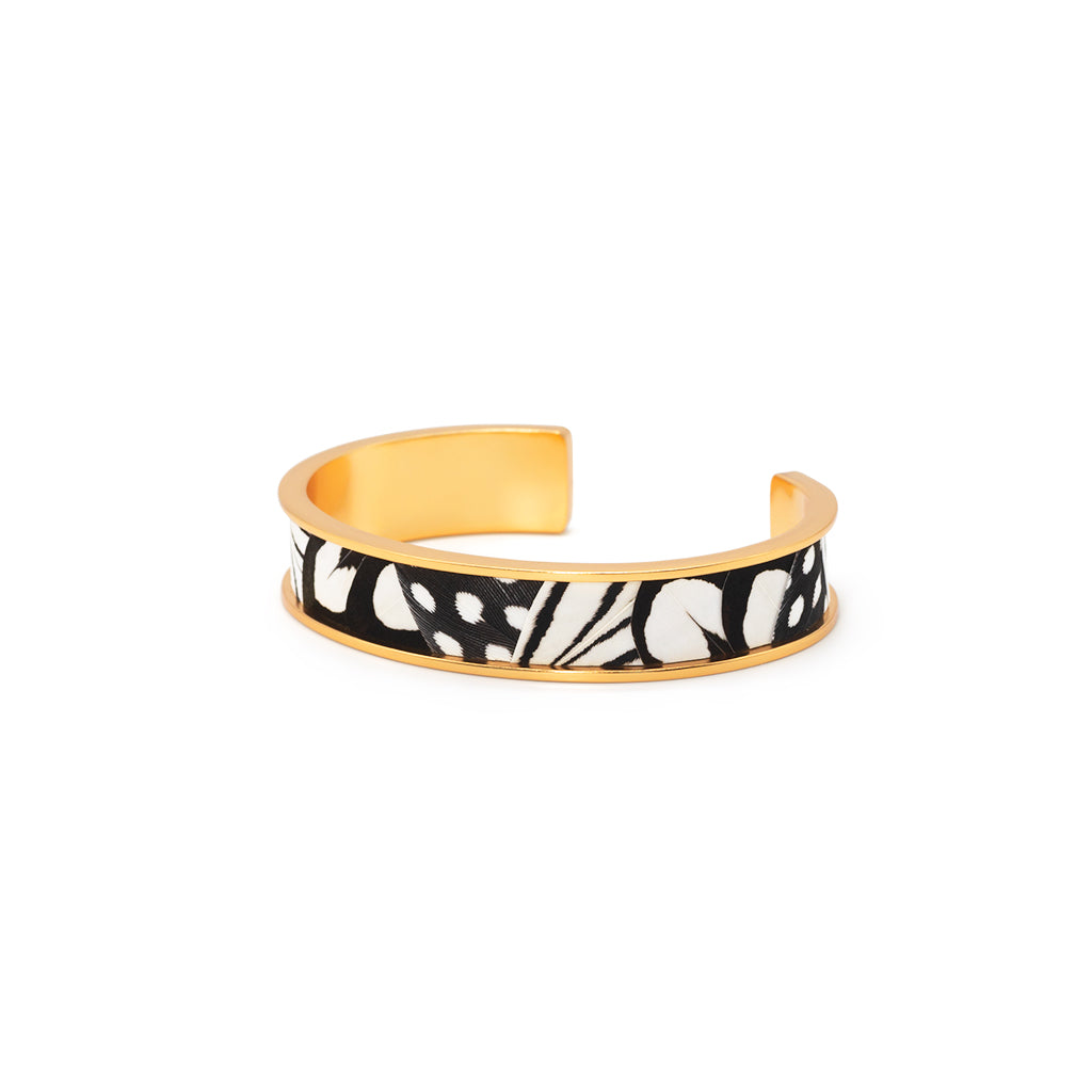 Gold cuff with black and white feather inlay on a white background