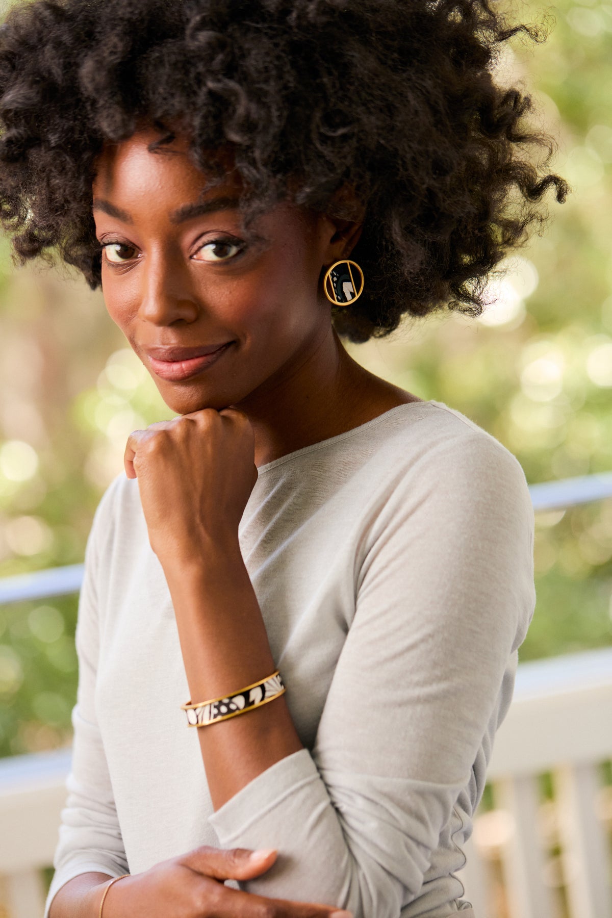 Woman in a white top modeling a gold cuff with black and white feather inlay.