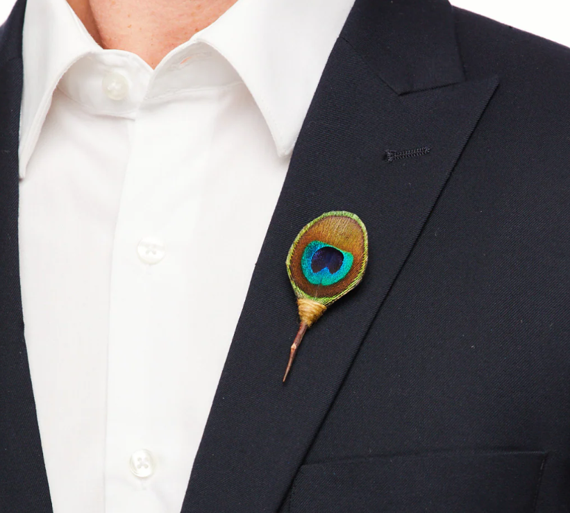 Peacock feather lapel pin on a on a black blazer.