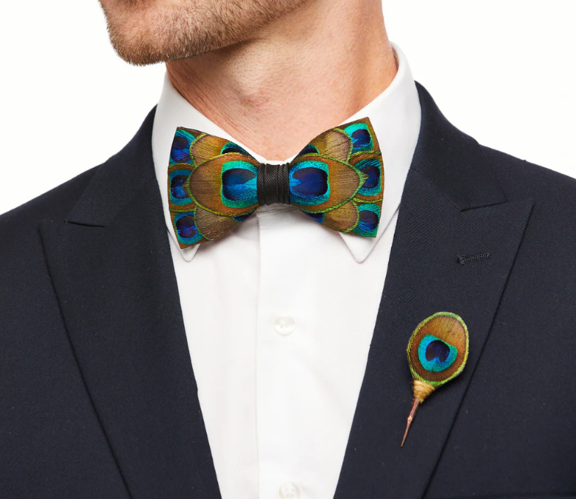 Man wearing a peacock feather lapel pin on a black blazer with matching peacock feather bowtie.