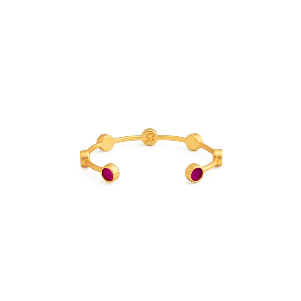 Brackish logo shown on back of gold cuff with round inlays of fuchsia feathers on a white background