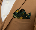 Folded green, brown and yellow pocket square displayed in a brown blazer.