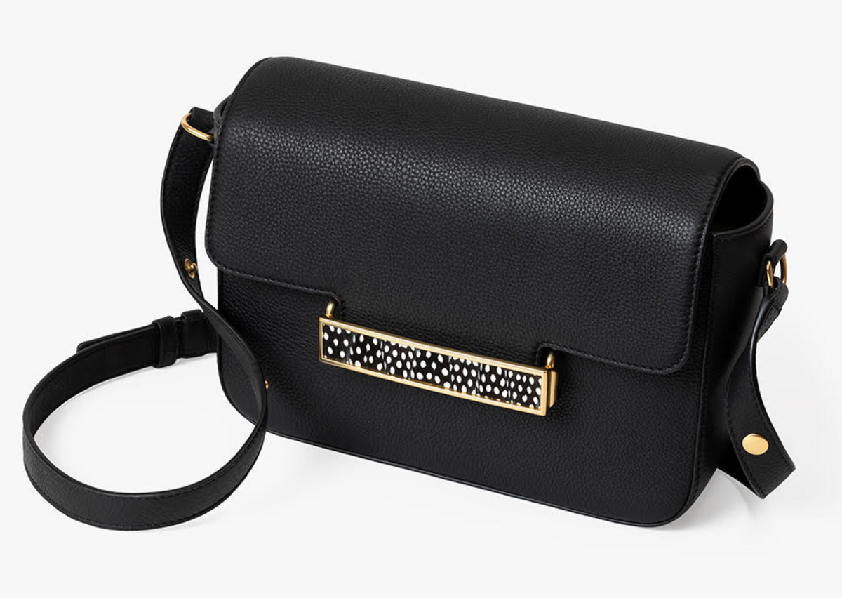 Overhead view of black leather handbag with gold clasp featuring a black and white feather inlay on a white background
