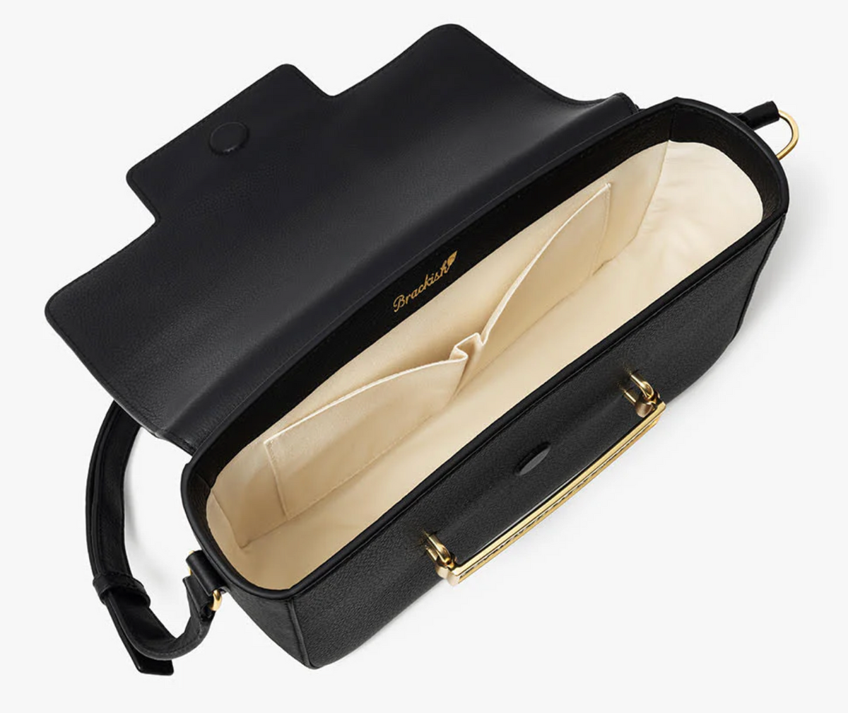 Overhead view of open black leather handbag with white, pocketed interior and gold exterior hardware on a white background. Brackish logo is visible on inside of handbag
