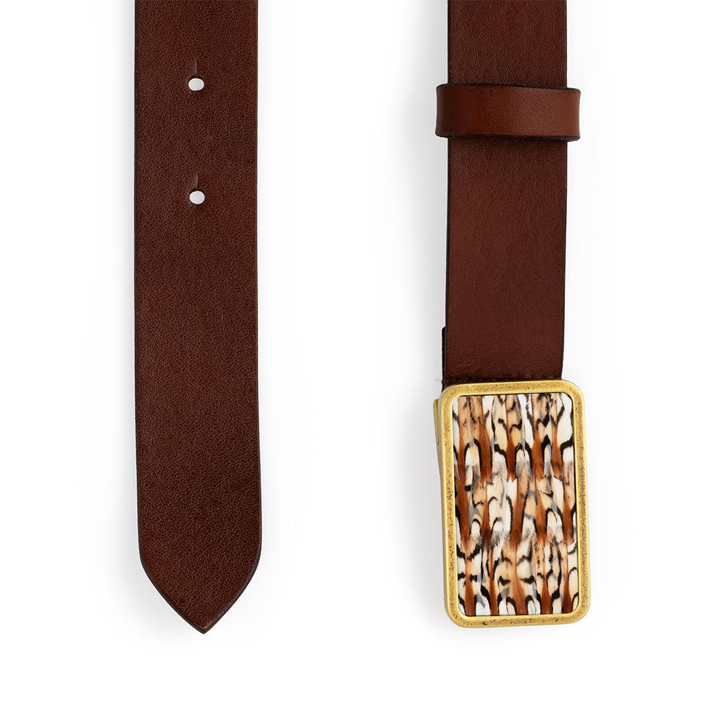 Both ends of a brown leather belt with a brown, black and white feather inlaid gold buckle on a white background