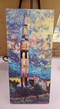 Artistic depiction of the Saturn V rocket at the US Space & Rocket Center with a colorful sky in the background