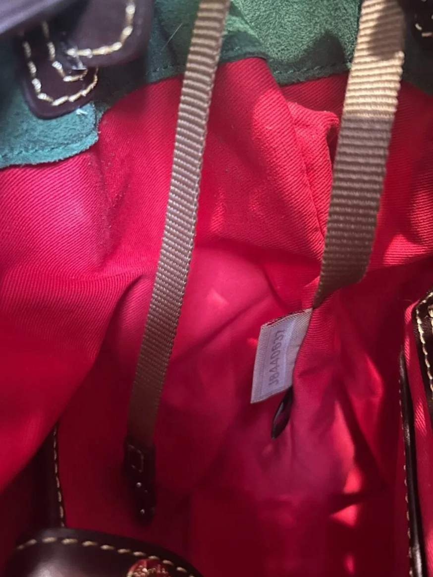 Close-up of a red bag with a visible brand label, green fabric, and brown strap.