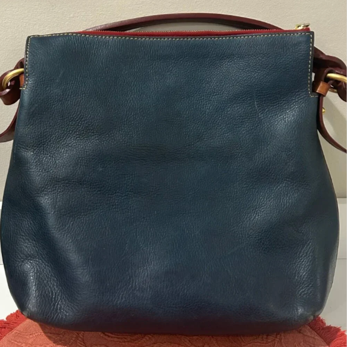 Blue leather handbag with brown handles on a light background