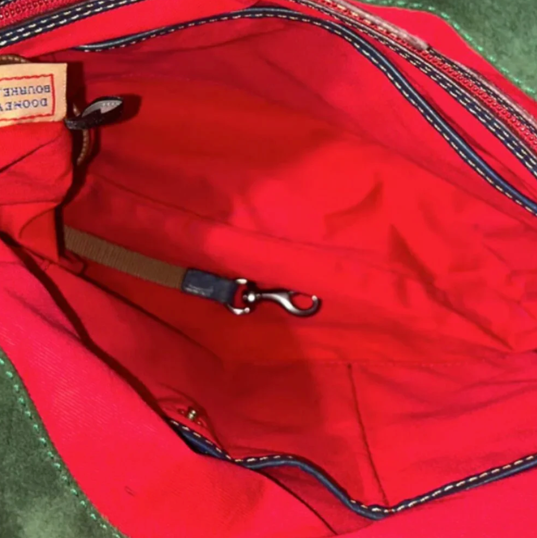 Close-up of a red bag with a visible brand label on a green background
