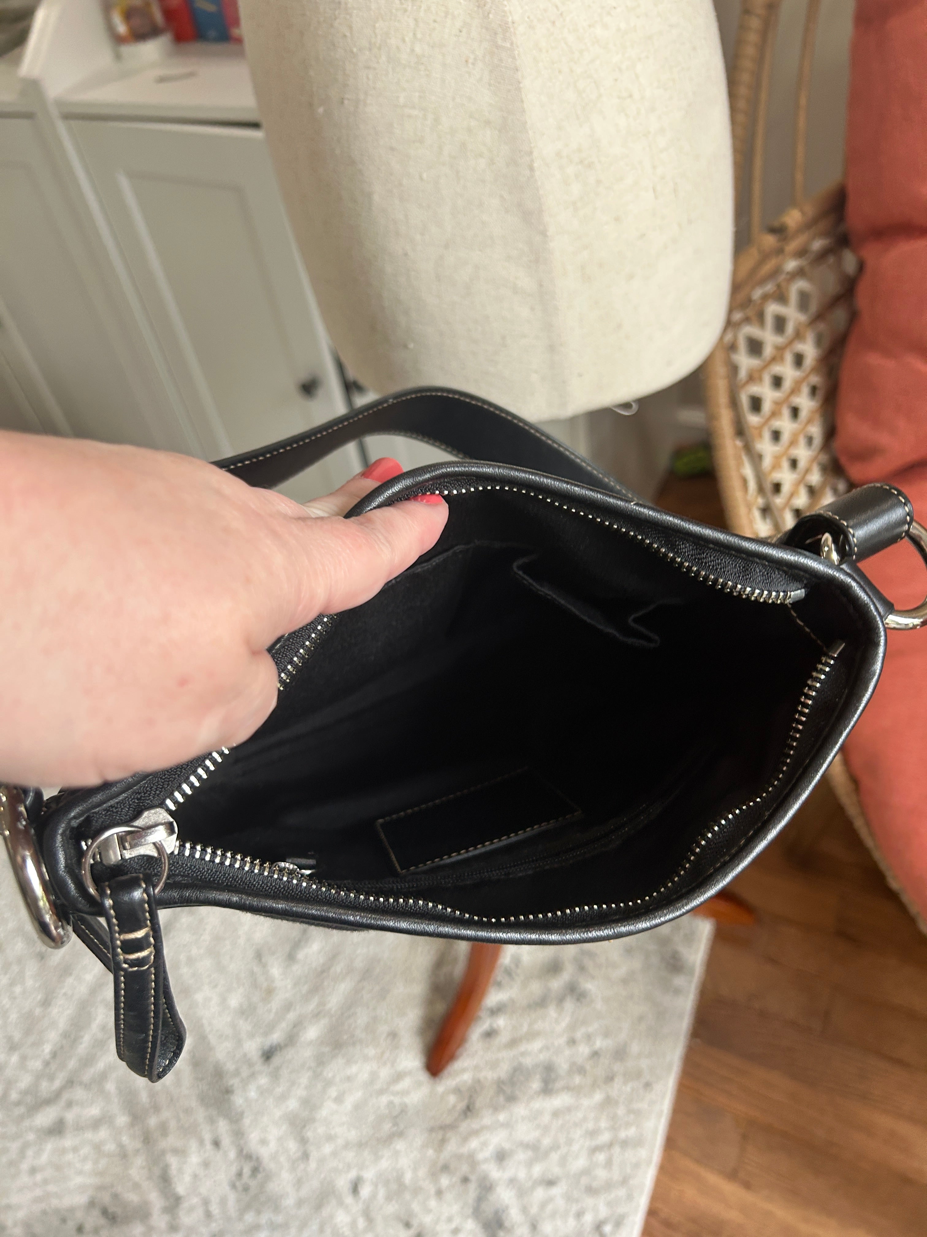 Black handbag with a hand pointing into it