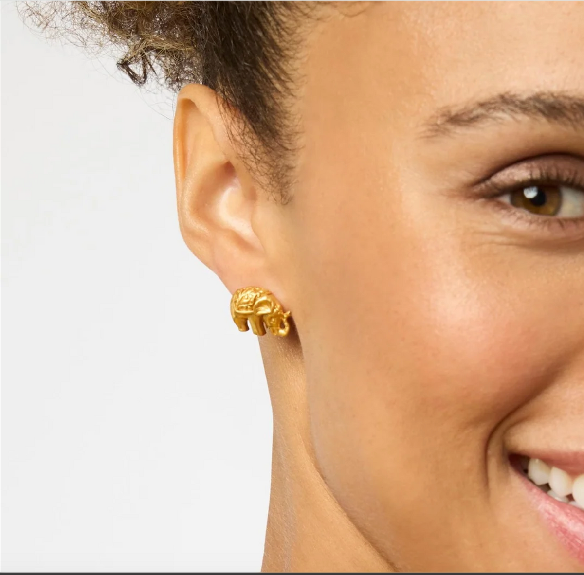 A woman wearing gold elephant studs