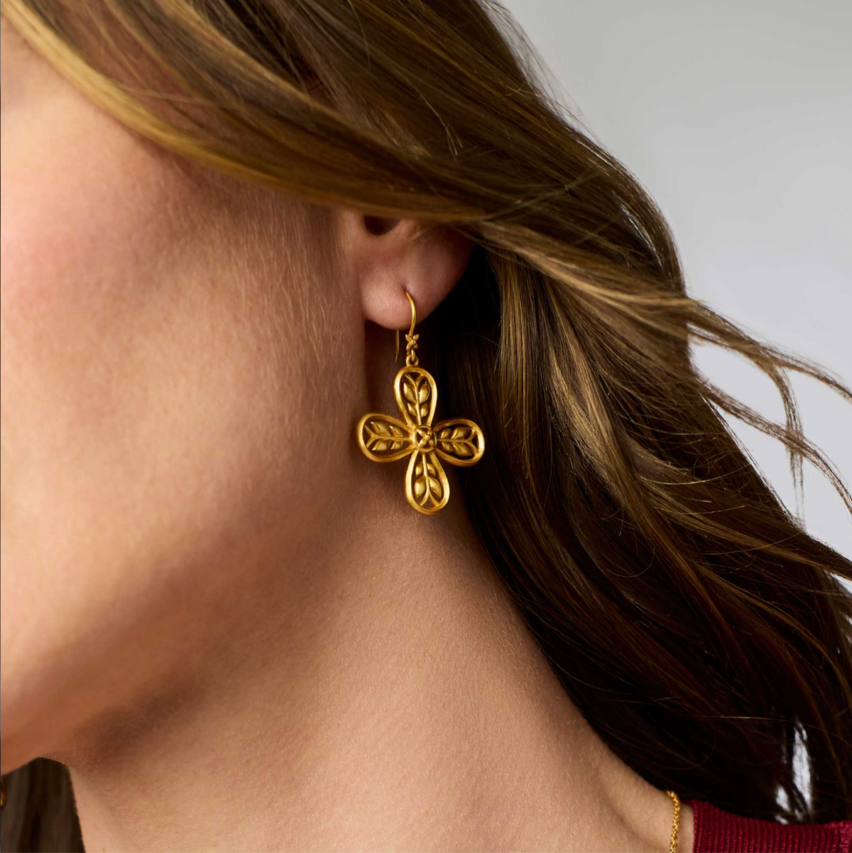 A woman is wearing gold floral earrings