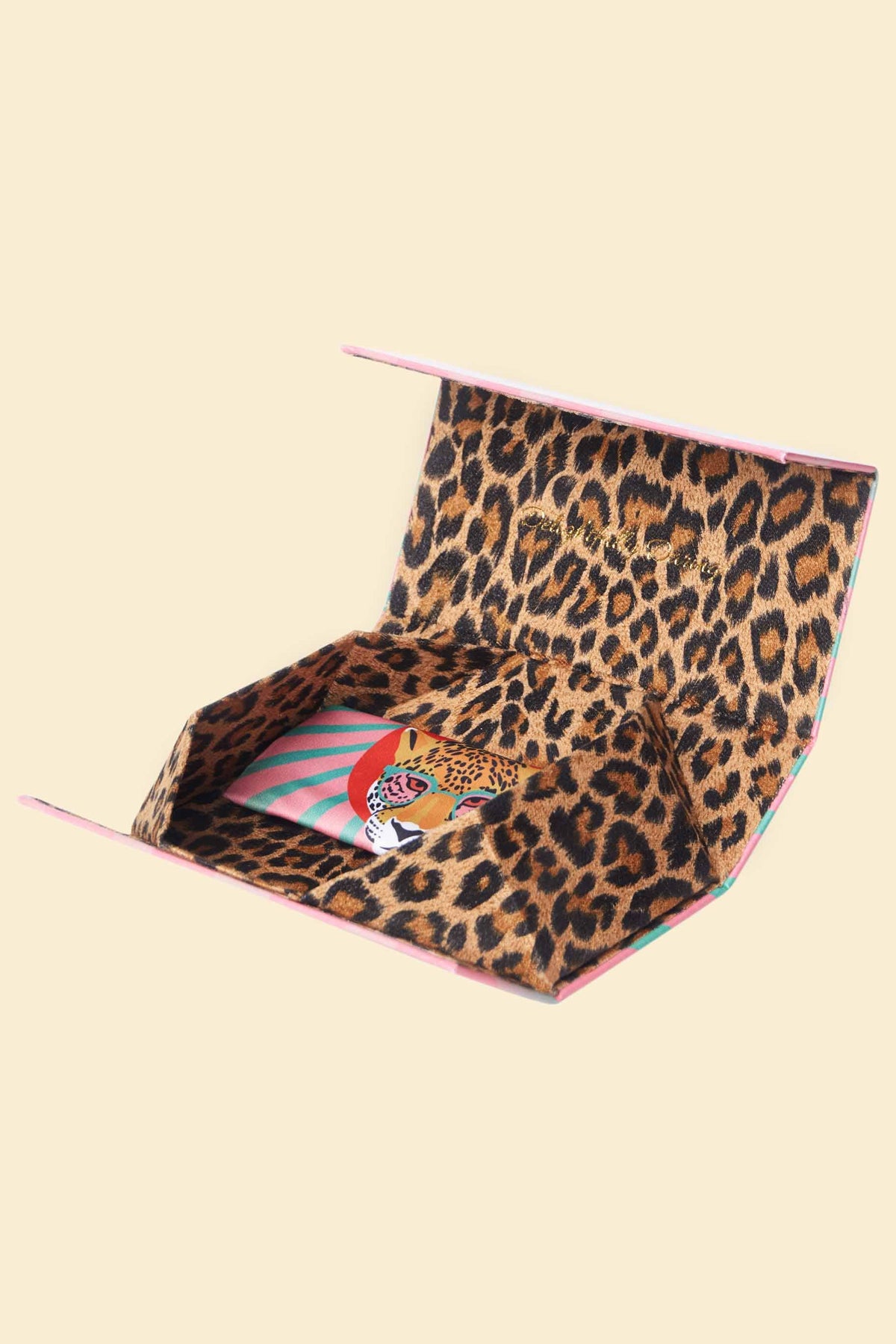 Open leopard print storage box for sunglasses on a beige background