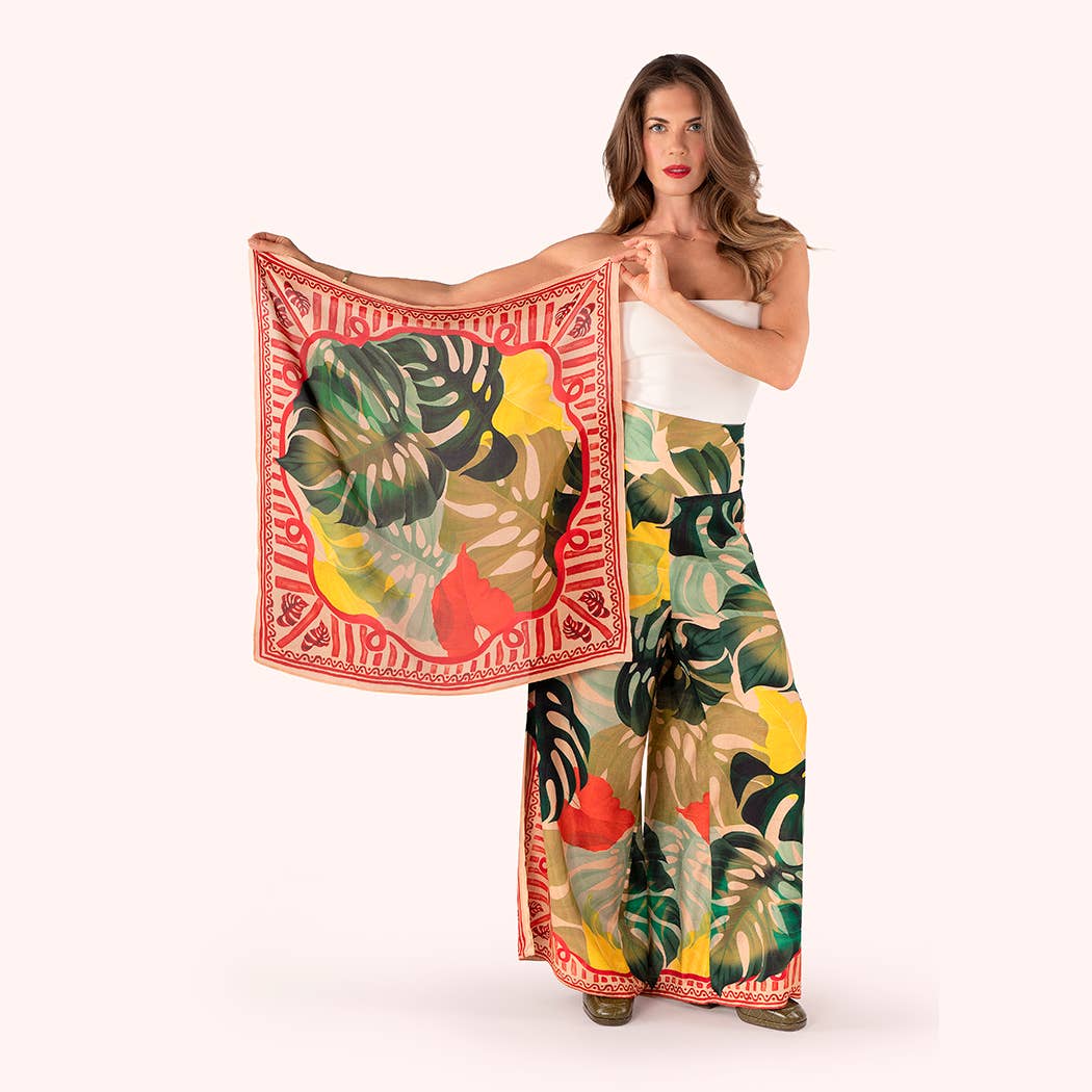 Woman holding a colorful scarf with tropical leaf design on a white background