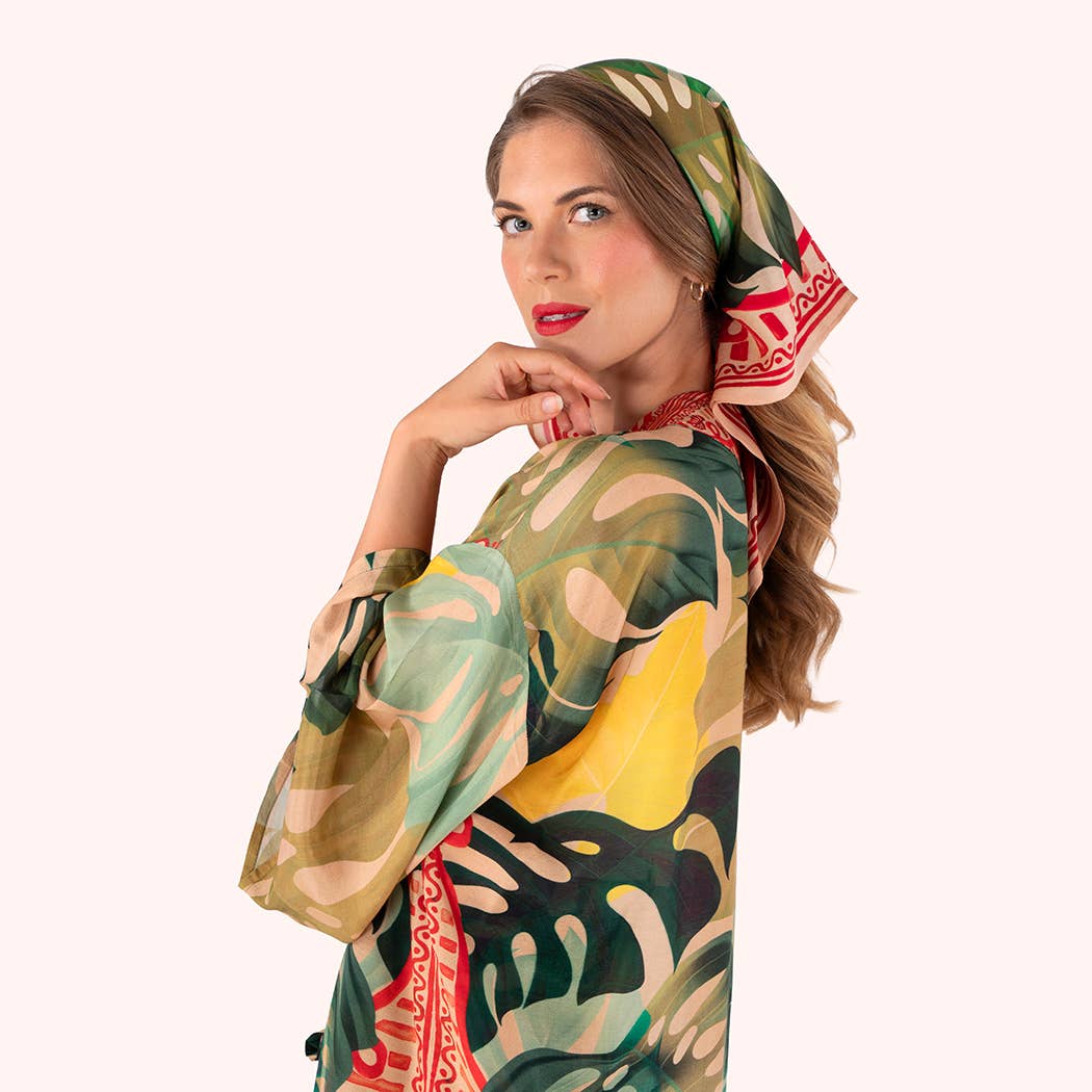 Woman wearing a colorful patterned headscarf and dress on a white background