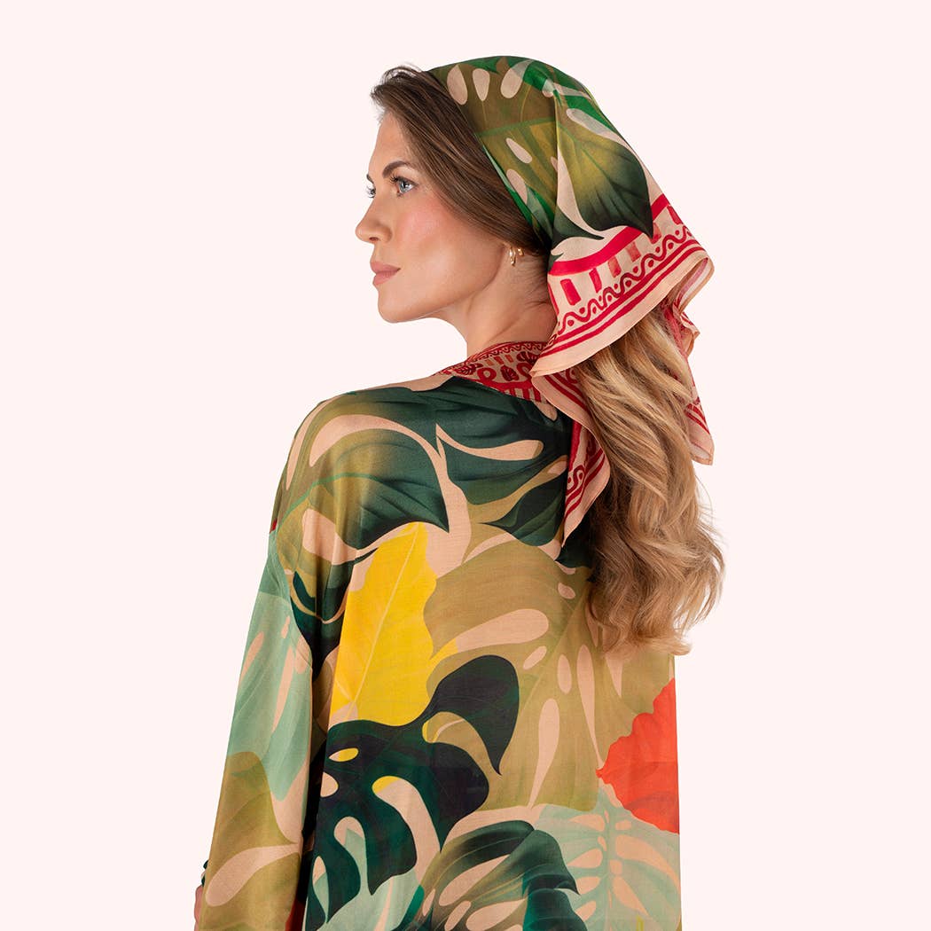 Woman wearing a colorful scarf with a tropical leaf pattern on a white background