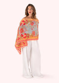 Woman wearing a colorful floral scarf with white pants on a white background