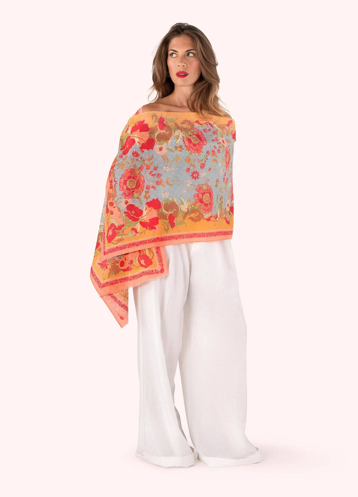 Woman wearing a colorful floral scarf with white pants on a white background