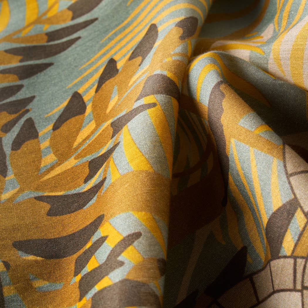 Close-up of fabric with a leaf pattern in brown, yellow, and gray.