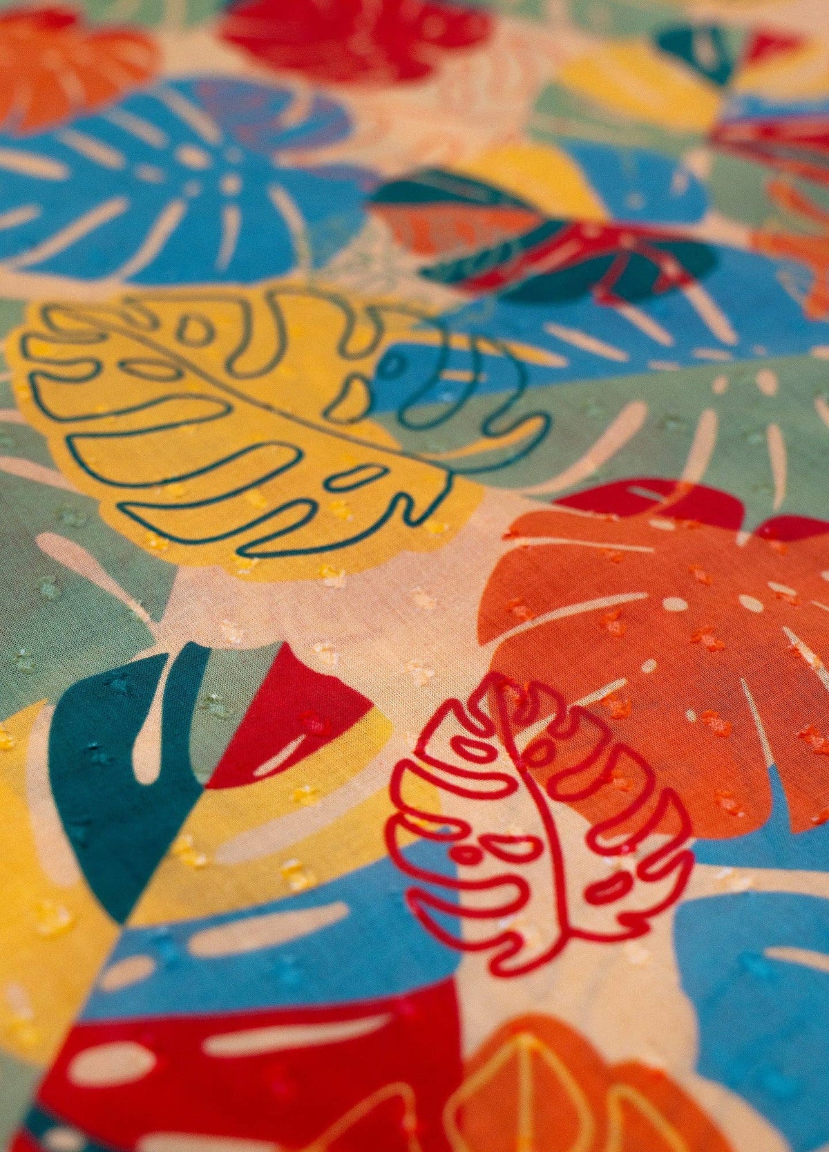 Close up of colorful abstract pattern featuring outlines of tropical leaves on a textured surface