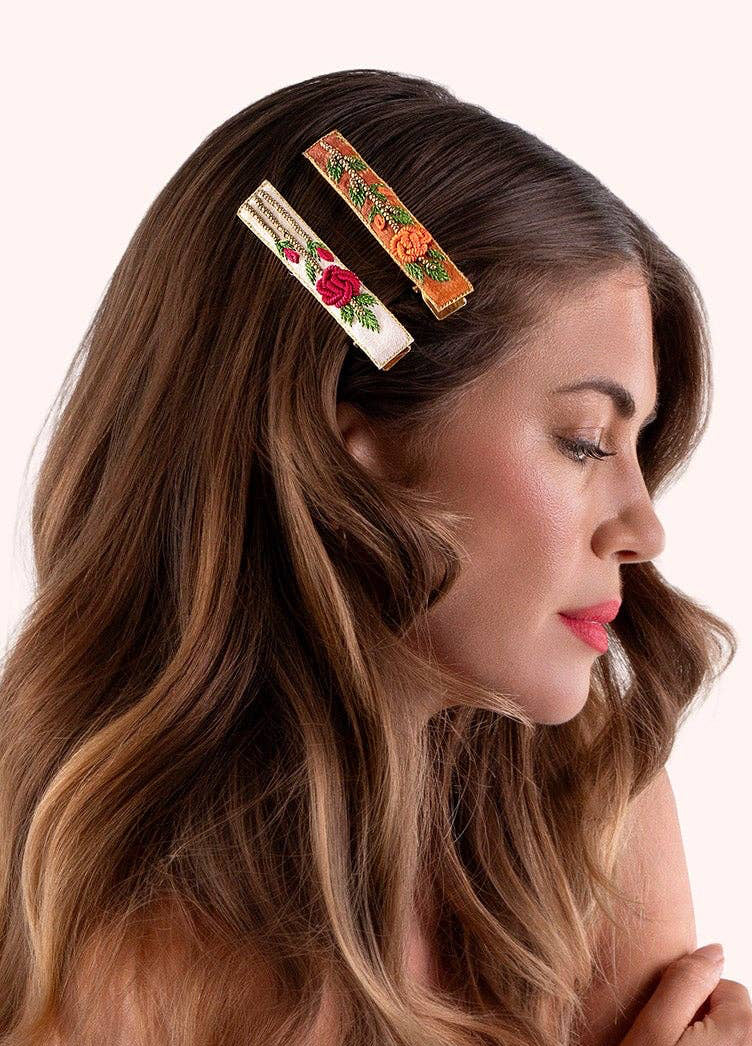 Woman wearing two colorful, rectangular floral hair clips on a white background