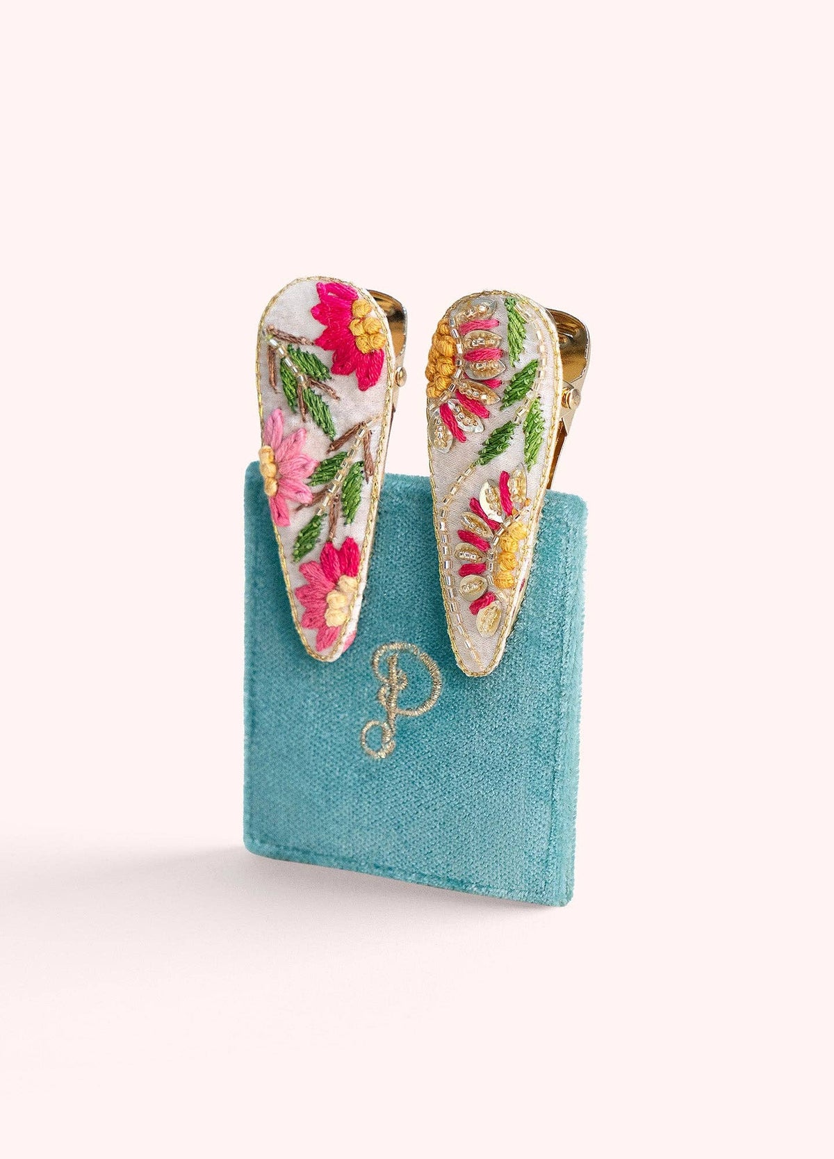 Colorful floral hair clips on a blue felt display with a white background
