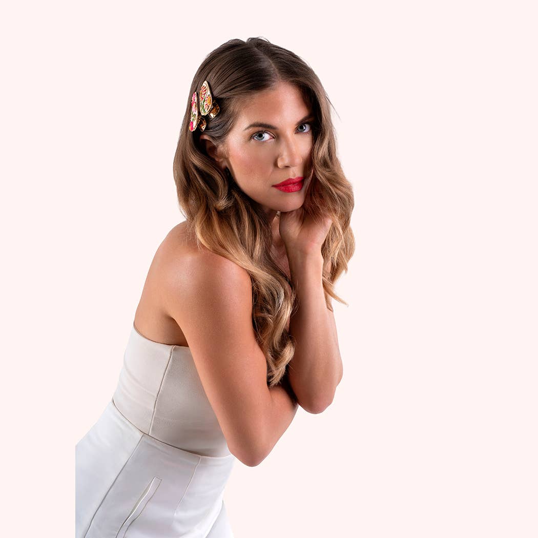 Woman with styled hair featuring two colorful floral hair clips posing against a white background