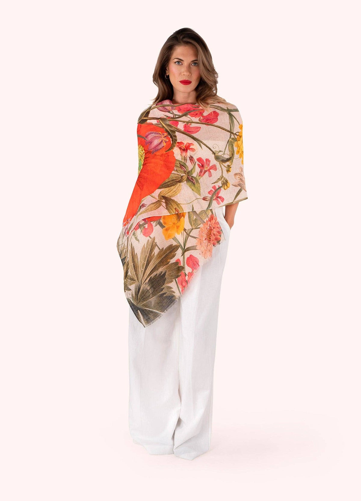 Woman wearing a floral patterned scarf with white pants on a white background