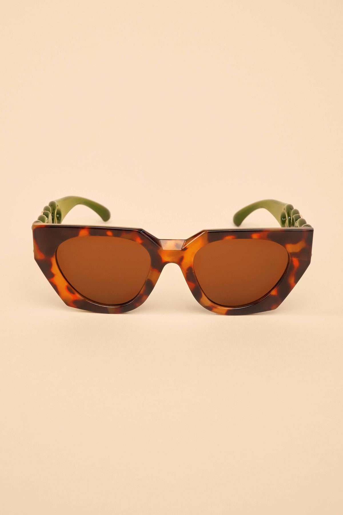 Sunglasses with olive tortoiseshell frame and brown lenses on a beige background