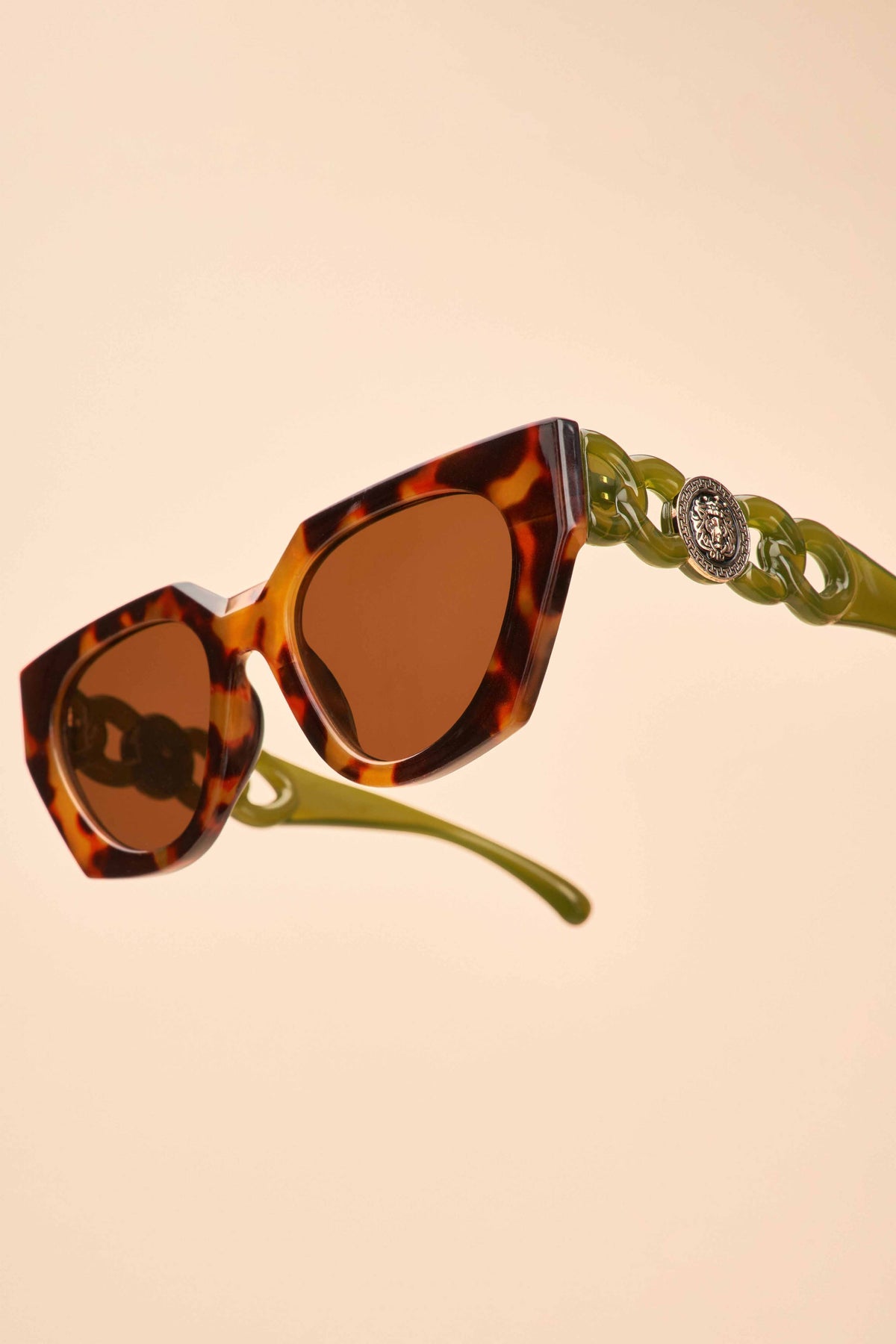 Low angle view of olive tortoiseshell sunglasses on a beige background