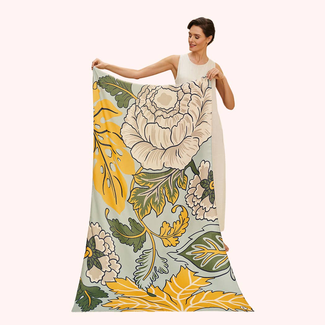 Woman displaying a floral-patterned scarf with yellow, green, and beige colors on a white background