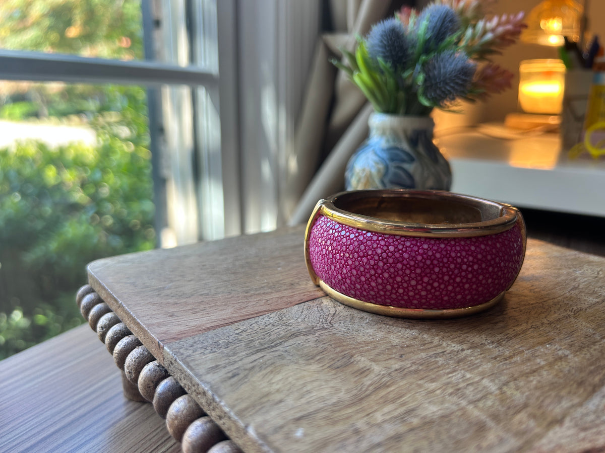 Pink and brass toned bracelet on a wood surface