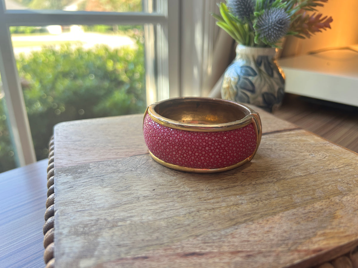 Pink and brass toned bracelet on a wooden surface