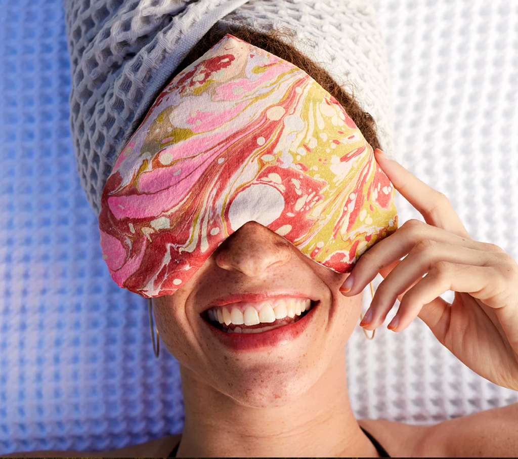 Person wearing a colorful eye mask with a marbled pattern, smiling.