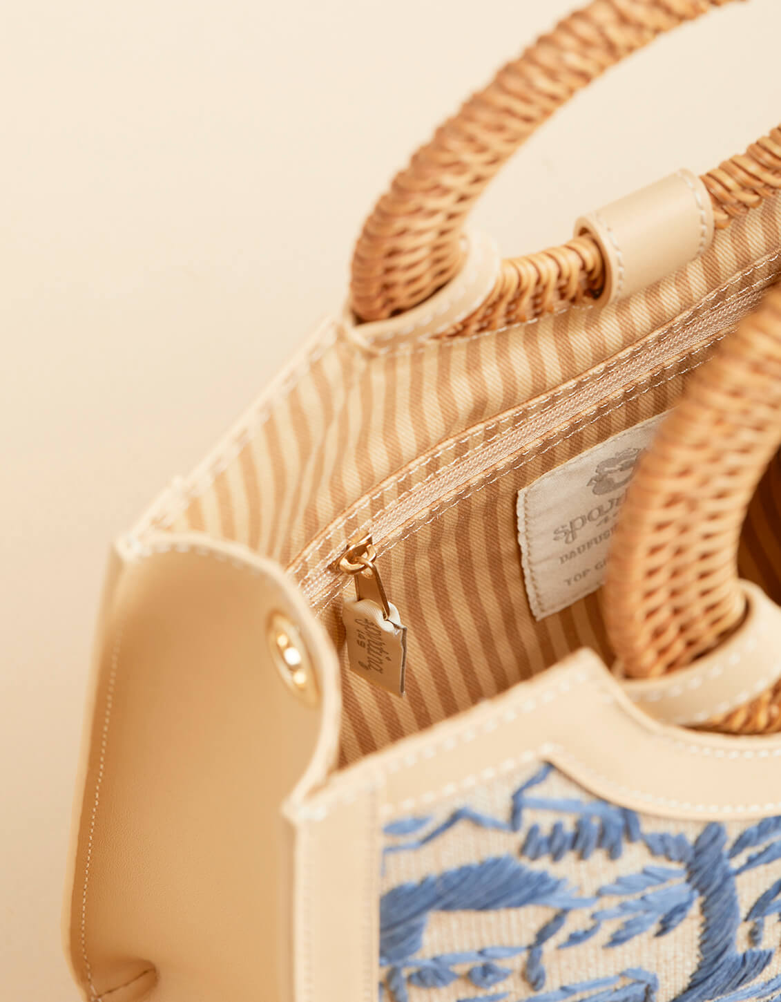 Close-up of a woven handbag with embroidery detail on a beige background