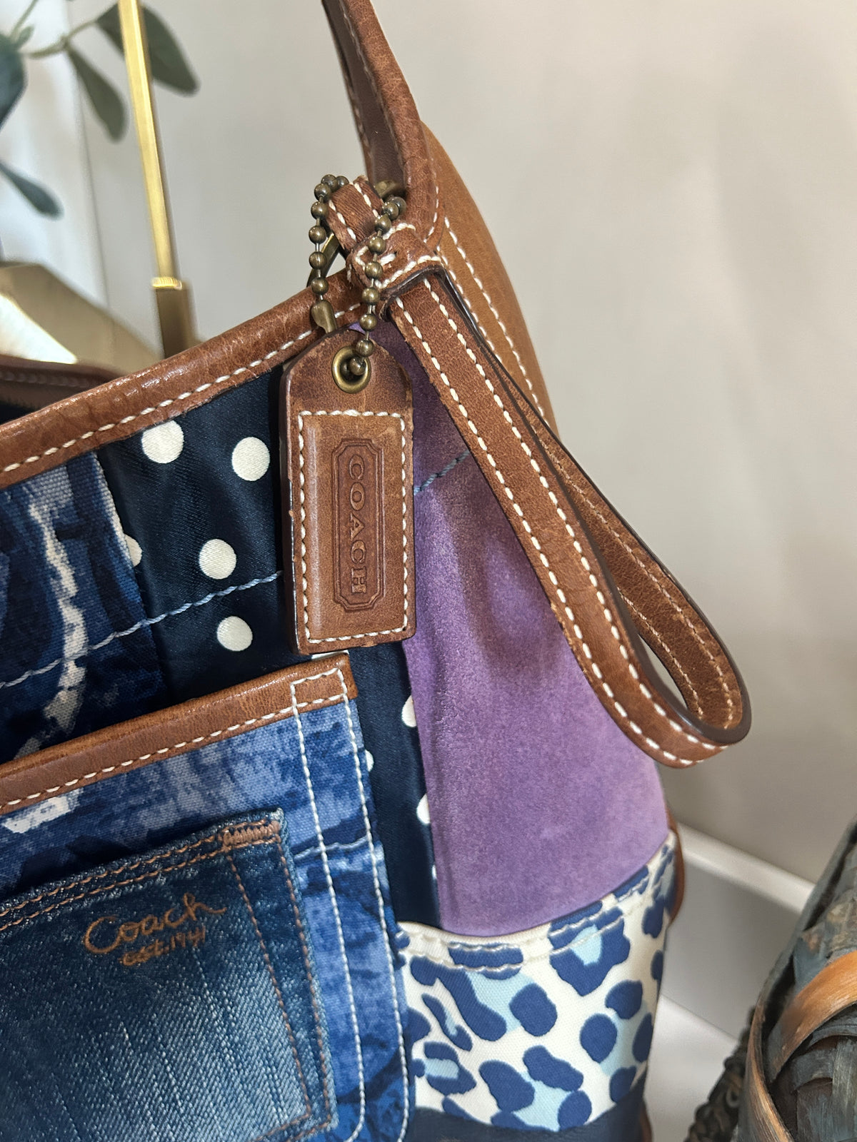 Closeup of a Coach branded hang tag on a blue, brown, and purple patchwork bag