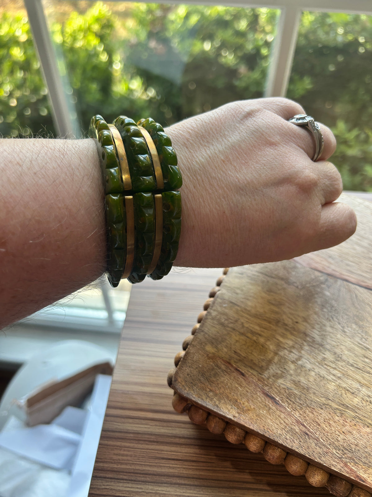 A green and brass toned bracelet on a woman's arm