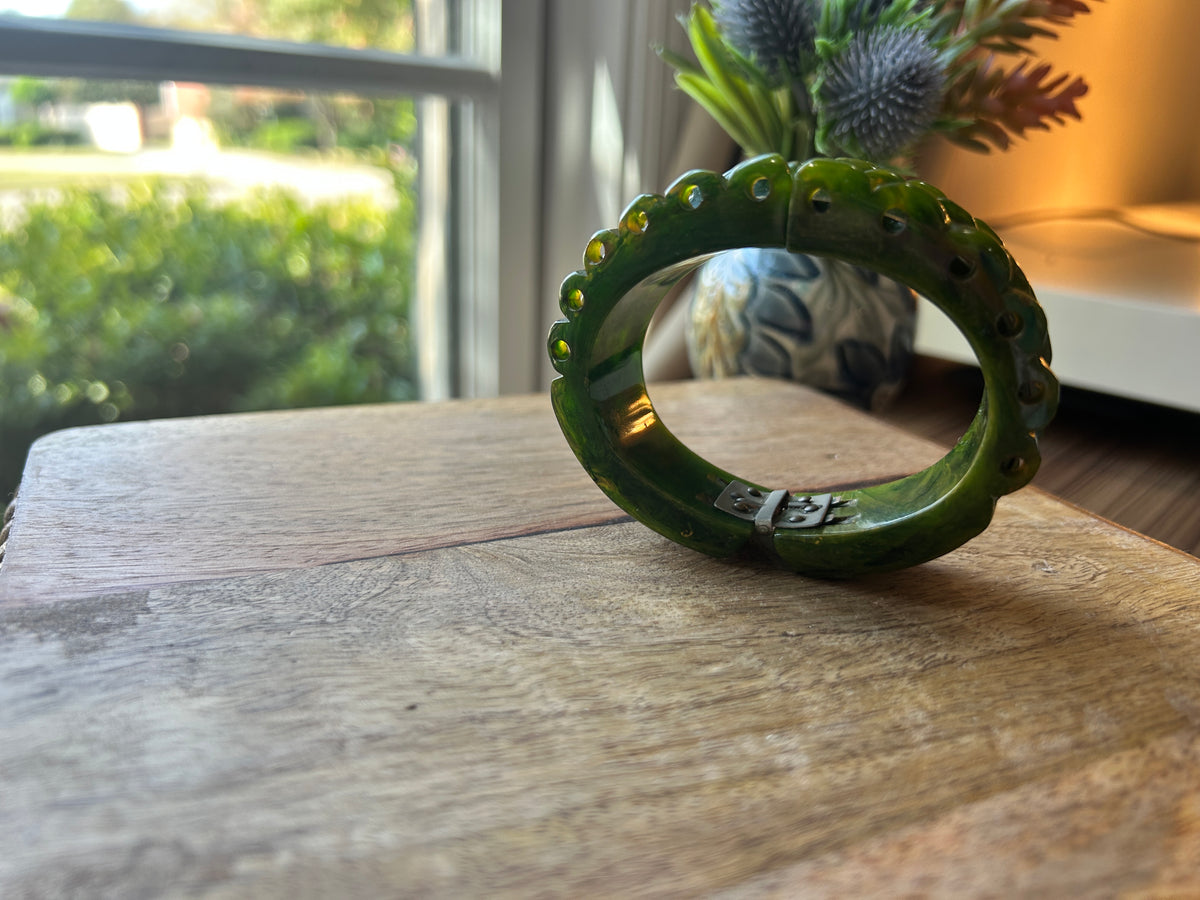 A green hinge bracelet on a wood surface