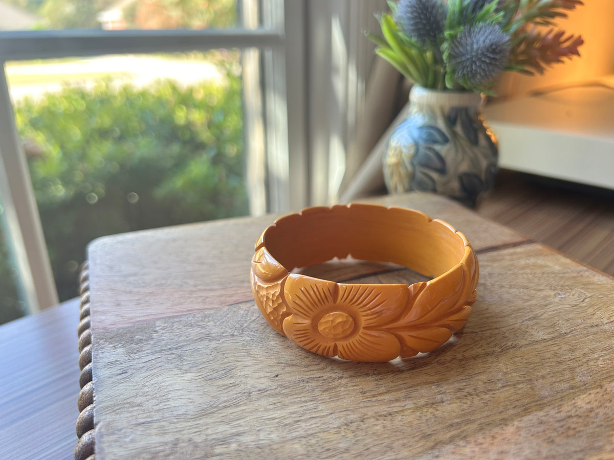A carved golden flower bangle on a wooden surface