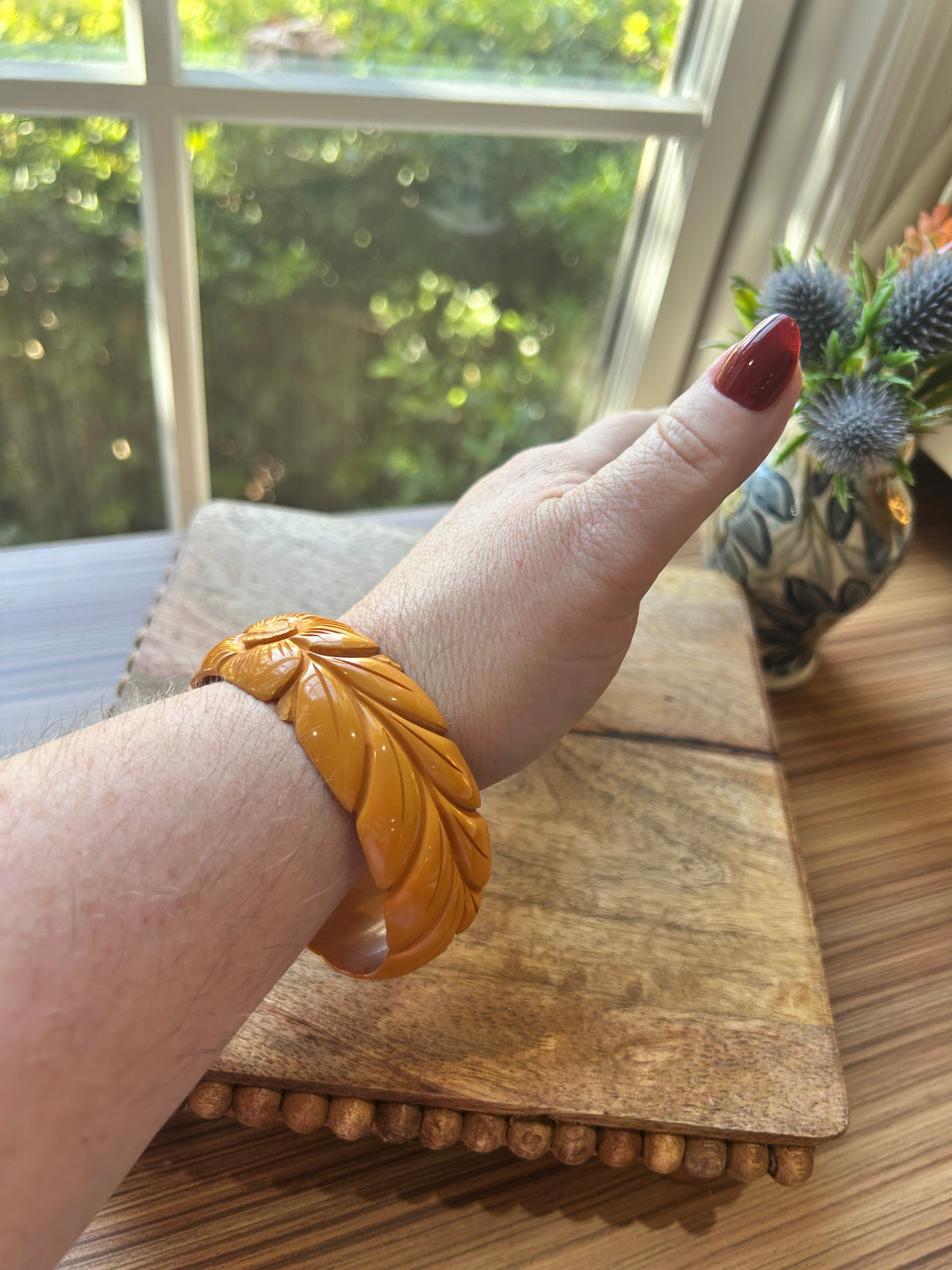 a carved golden yellow bangle on a woman's arm