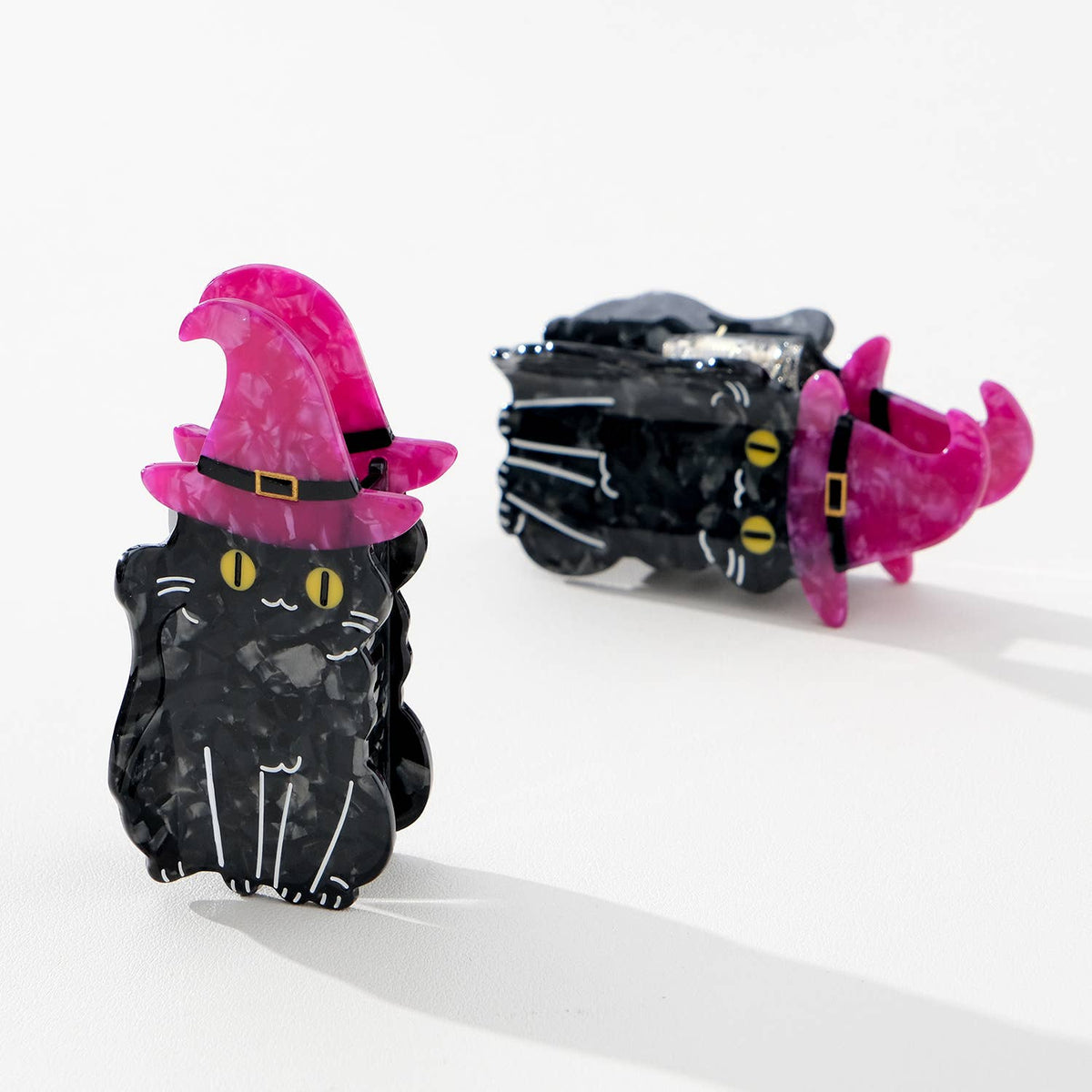 Black cat-shaped hairclips with purple witch hat on a white background