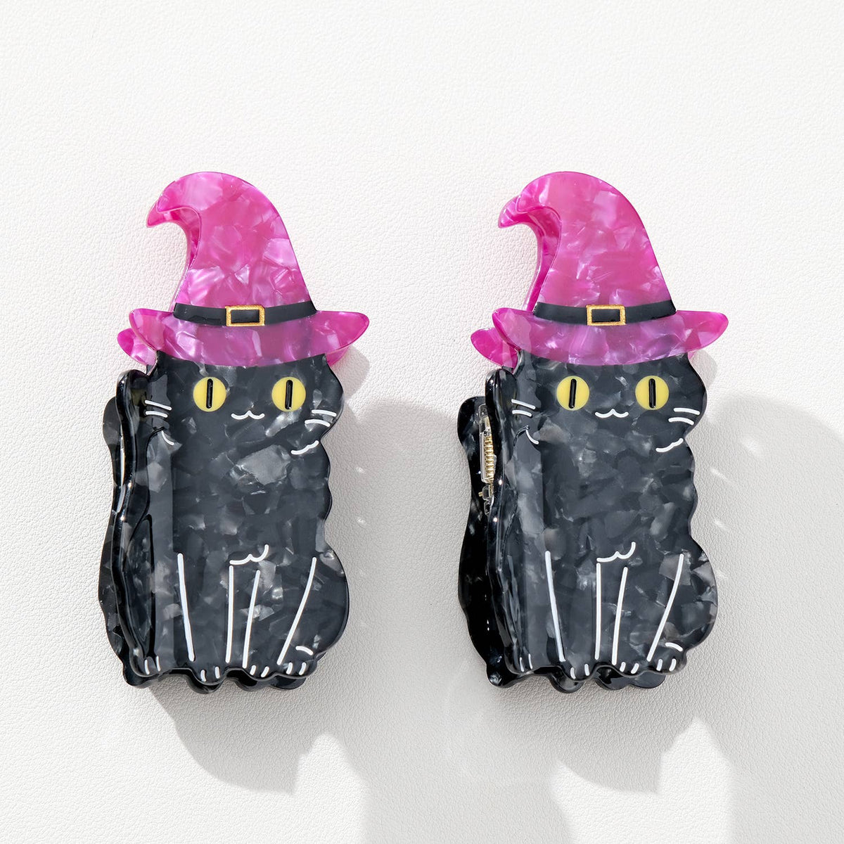 Black cat hair clips with purple witch hats on a white background